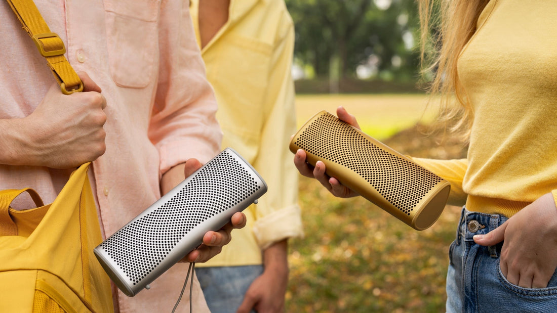 Two people holding a KEF Muo portable speaker in their hands 