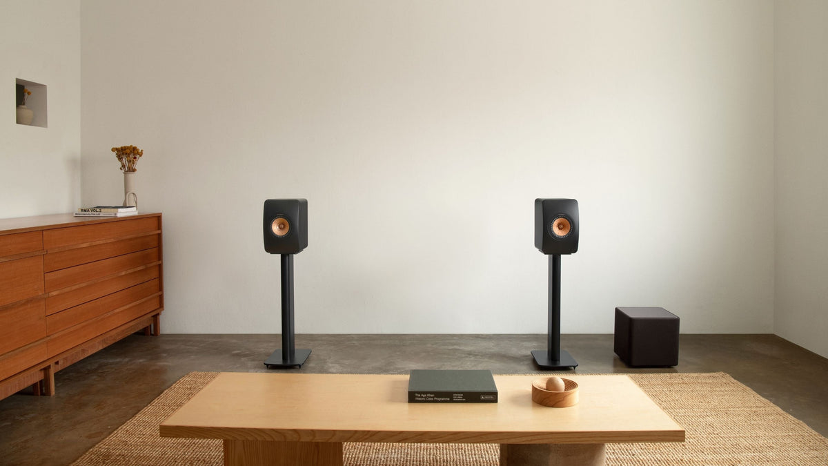 Home theater setup with LS50 Meta speakers and subwoofer in a room.