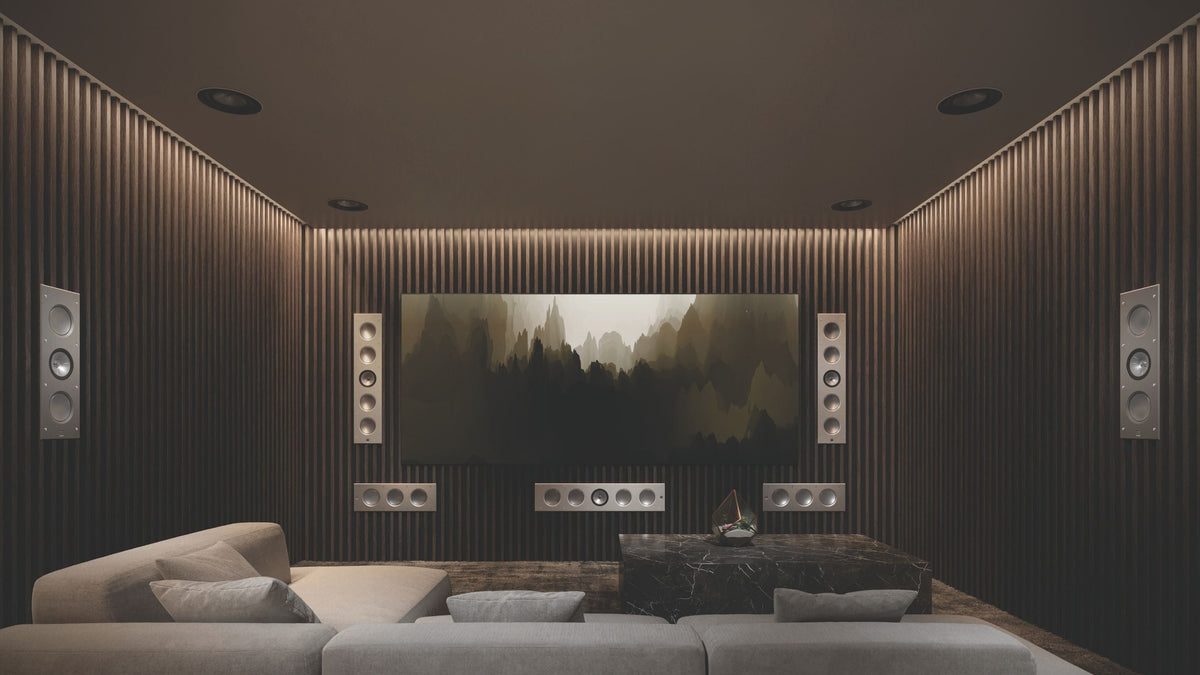 A sleek home theater setup with a large screen, displaying KEF architectural speakers  Ci5160RLM-THX speakers and smaller Ci3160RLM-THX speakers.