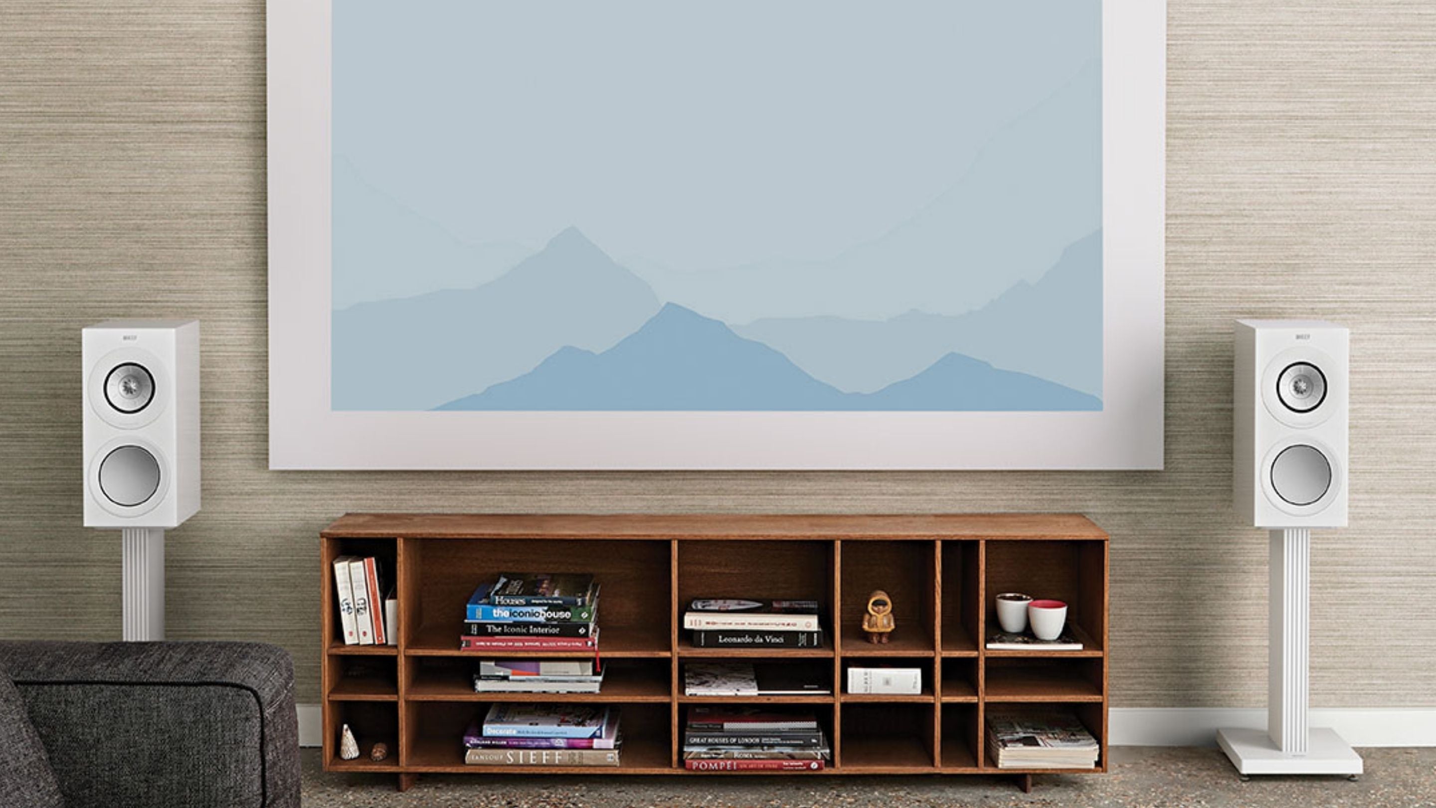 KEF R3 Meta Floor standing speaker mounted to a White S3 Floor stand accessory placed between bookshelf in a living room